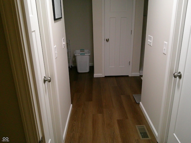 corridor featuring baseboards, visible vents, and dark wood finished floors