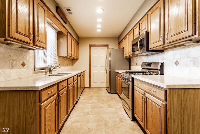 kitchen with brown cabinets, light countertops, visible vents, appliances with stainless steel finishes, and a sink