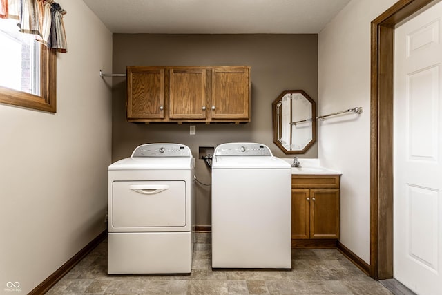 washroom featuring a sink, cabinet space, baseboards, and washer and dryer