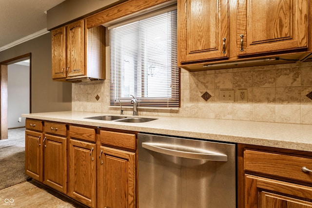 kitchen featuring light countertops, stainless steel dishwasher, brown cabinetry, ornamental molding, and a sink