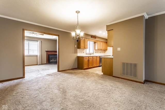 kitchen featuring crown molding, light countertops, visible vents, a glass covered fireplace, and baseboards