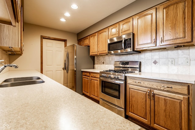 kitchen featuring a sink, light countertops, appliances with stainless steel finishes, brown cabinets, and tasteful backsplash