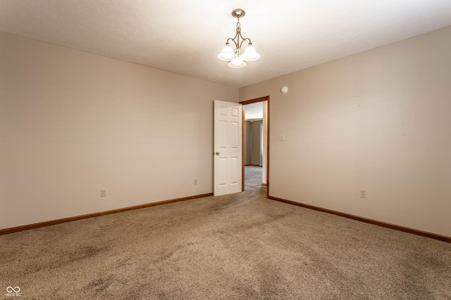 spare room featuring light carpet, baseboards, and a chandelier