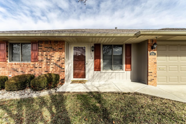 doorway to property featuring a garage and brick siding