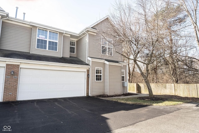 view of front of property with brick siding, fence, and driveway