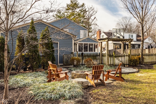 rear view of house with a sunroom, fence, a fire pit, and a pergola