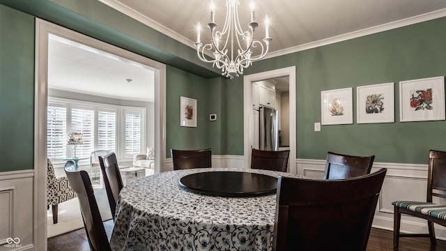 dining area featuring ornamental molding, wainscoting, dark wood finished floors, and a notable chandelier