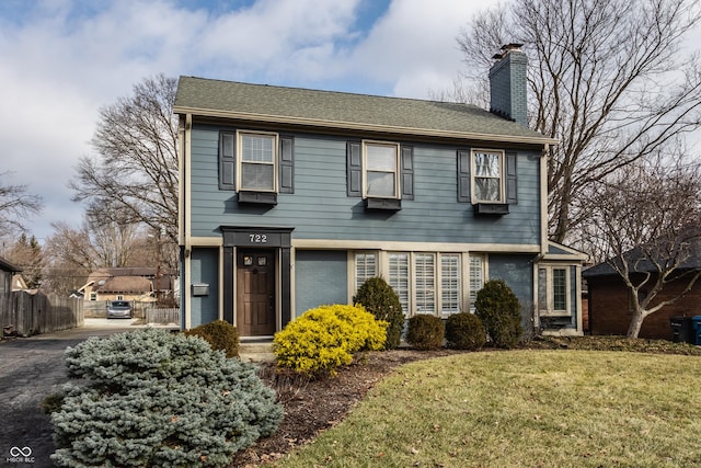 colonial-style house with a chimney and a front lawn