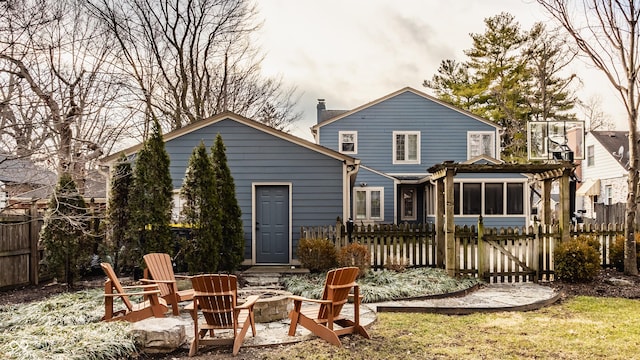 back of house featuring a chimney, fence, and a fire pit