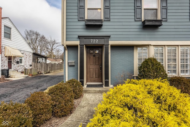 entrance to property featuring brick siding and fence