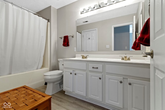 bathroom featuring double vanity, visible vents, toilet, wood finished floors, and a sink