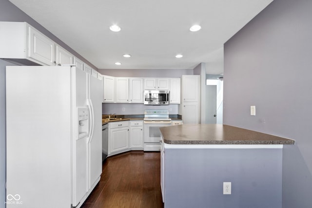 kitchen with a peninsula, dark wood-type flooring, white cabinetry, appliances with stainless steel finishes, and dark countertops