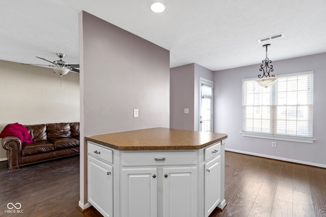 kitchen with dark countertops, dark wood-style floors, visible vents, and white cabinets