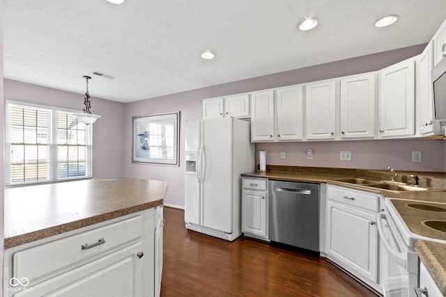 kitchen with dark wood finished floors, stainless steel appliances, visible vents, white cabinetry, and a sink