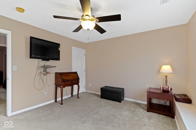 sitting room featuring a ceiling fan, light carpet, and baseboards