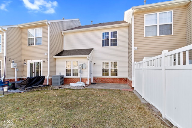 rear view of house with central AC unit, brick siding, fence, a yard, and a patio area