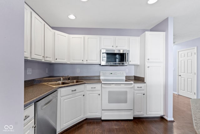 kitchen featuring dark countertops, appliances with stainless steel finishes, white cabinets, and a sink