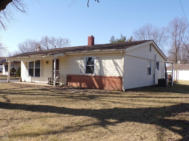 rear view of property featuring a yard, central air condition unit, brick siding, and a chimney