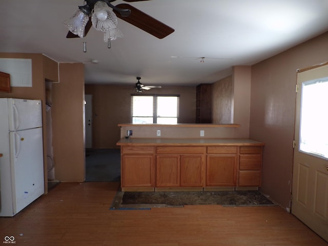 kitchen with light wood-type flooring, brown cabinets, light countertops, and freestanding refrigerator