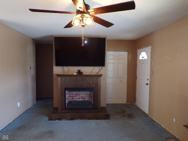 unfurnished living room featuring a fireplace with raised hearth and ceiling fan