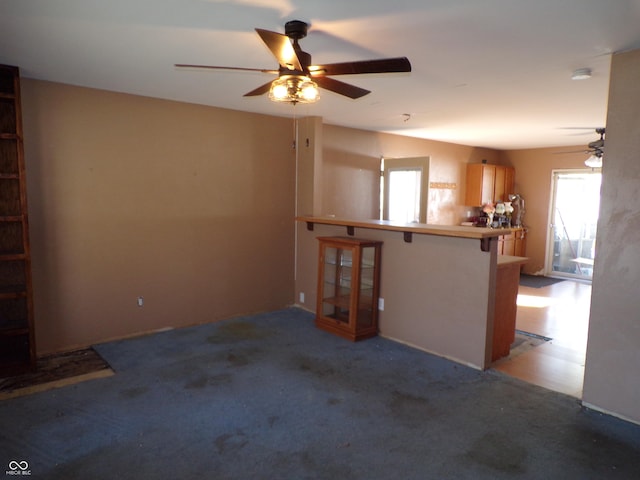 unfurnished living room featuring a ceiling fan and carpet floors