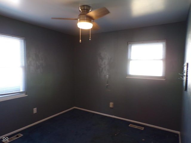 empty room featuring visible vents, a ceiling fan, and baseboards