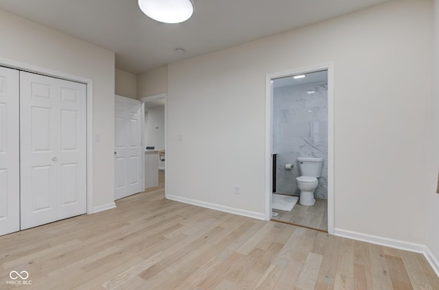 unfurnished bedroom with a closet, ensuite bath, light wood-style flooring, and baseboards