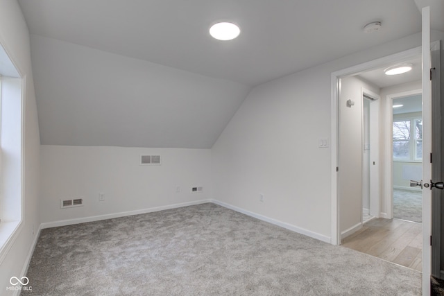 additional living space featuring lofted ceiling, carpet floors, and visible vents