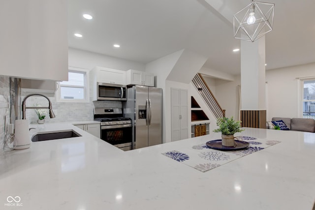 kitchen featuring appliances with stainless steel finishes, a wealth of natural light, white cabinetry, and a sink