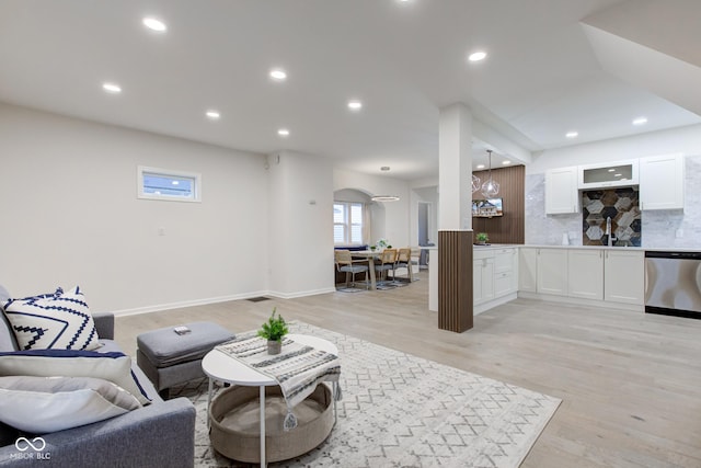 living room featuring light wood-style flooring, arched walkways, baseboards, and recessed lighting