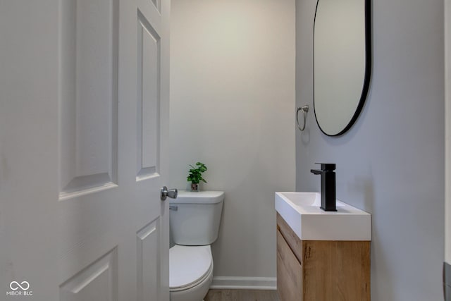 bathroom with toilet, baseboards, wood finished floors, and vanity