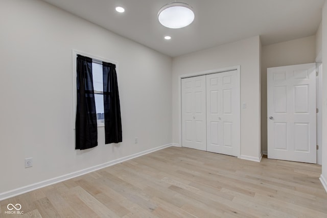 unfurnished bedroom with light wood-type flooring, a closet, baseboards, and recessed lighting