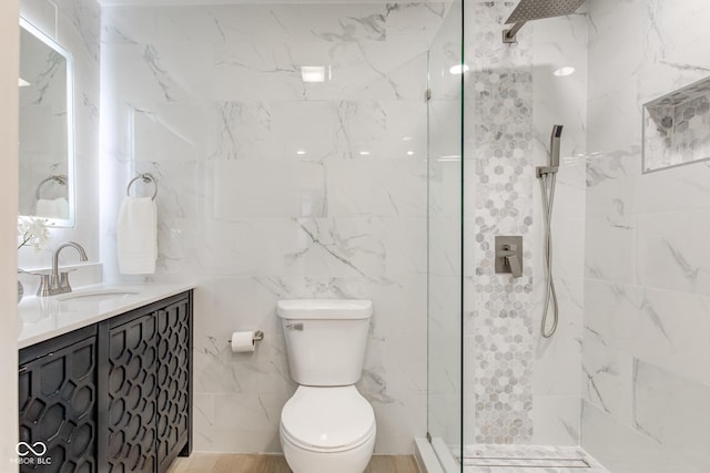 bathroom featuring tile walls, tiled shower, vanity, and toilet