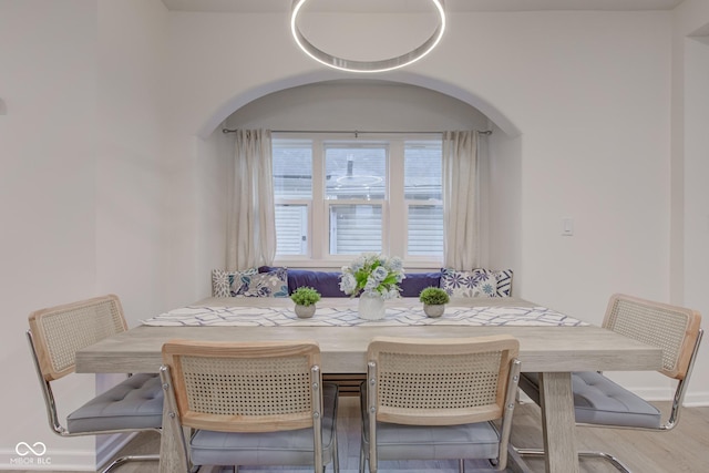 dining room featuring arched walkways and wood finished floors