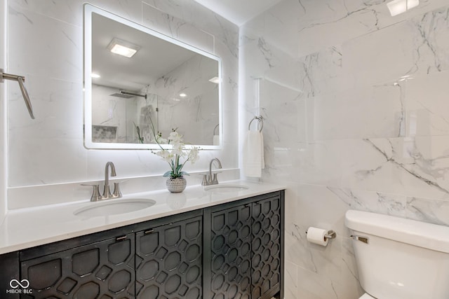 full bathroom featuring a sink, tile walls, toilet, and double vanity