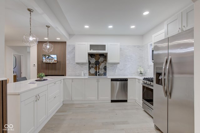 kitchen featuring stainless steel appliances, light wood-style flooring, decorative backsplash, white cabinetry, and a peninsula