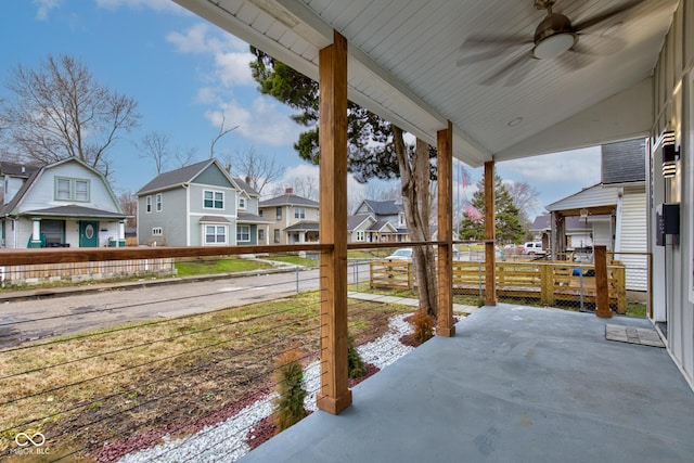 view of patio featuring ceiling fan, a porch, fence, and a residential view