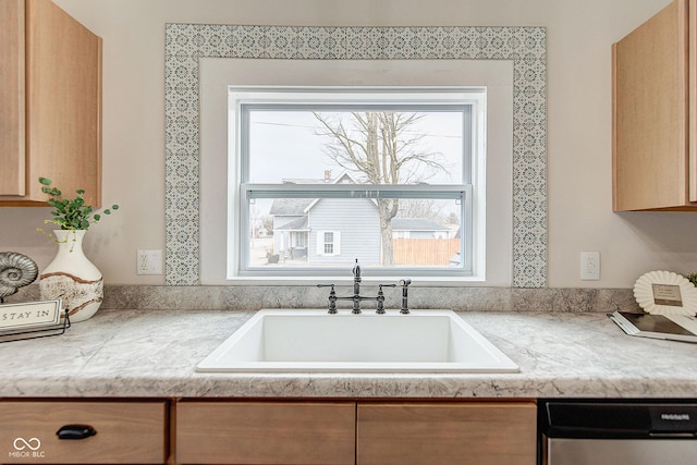 kitchen featuring dishwashing machine, plenty of natural light, light countertops, and a sink