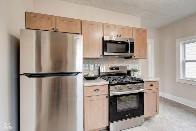 kitchen featuring stainless steel appliances, light countertops, decorative backsplash, a textured ceiling, and baseboards