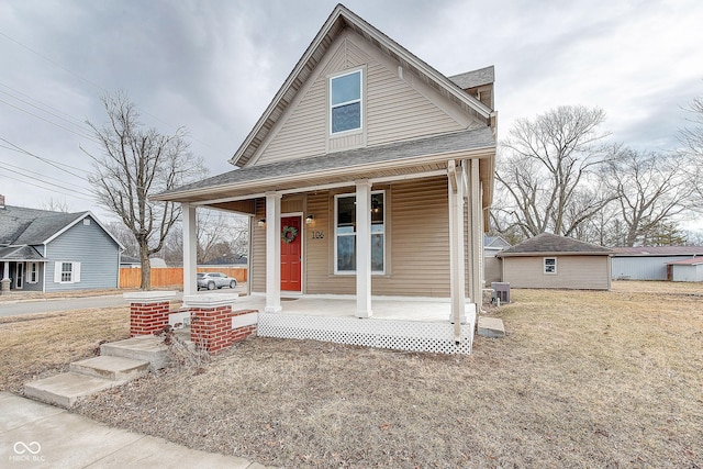 view of front of home with covered porch, a shingled roof, and cooling unit