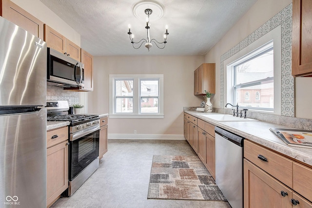 kitchen featuring a healthy amount of sunlight, appliances with stainless steel finishes, light countertops, and a sink