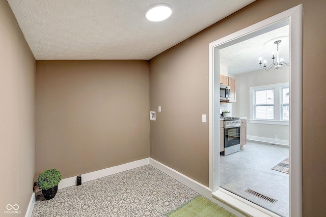 clothes washing area with a notable chandelier, baseboards, visible vents, and a textured ceiling