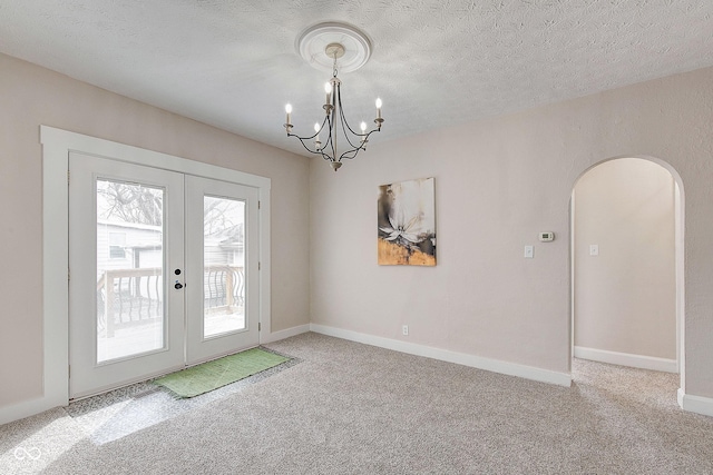 entryway with carpet floors, arched walkways, a textured ceiling, and french doors