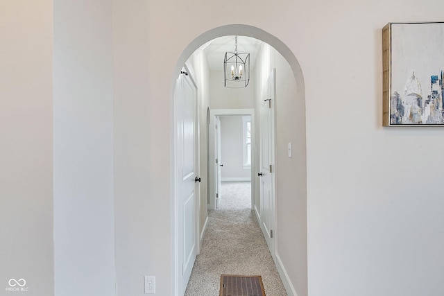 corridor featuring carpet, visible vents, arched walkways, and baseboards