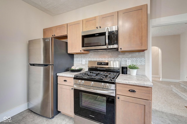 kitchen with stainless steel appliances, backsplash, and baseboards