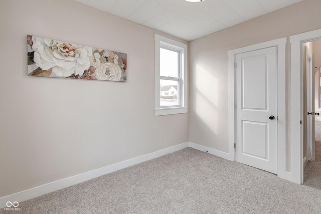 carpeted spare room featuring baseboards