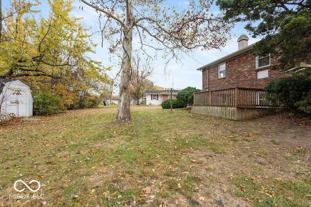 view of yard featuring an outbuilding, a wooden deck, and a shed