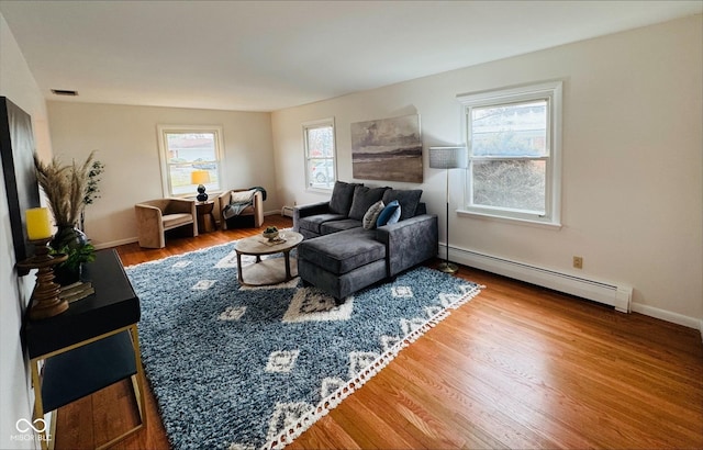 living room featuring a baseboard radiator, visible vents, baseboards, and wood finished floors