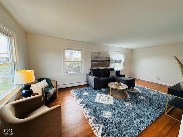 living area featuring a baseboard heating unit, wood finished floors, and baseboards