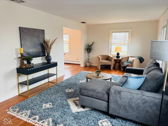 living room featuring baseboard heating, wood finished floors, and baseboards